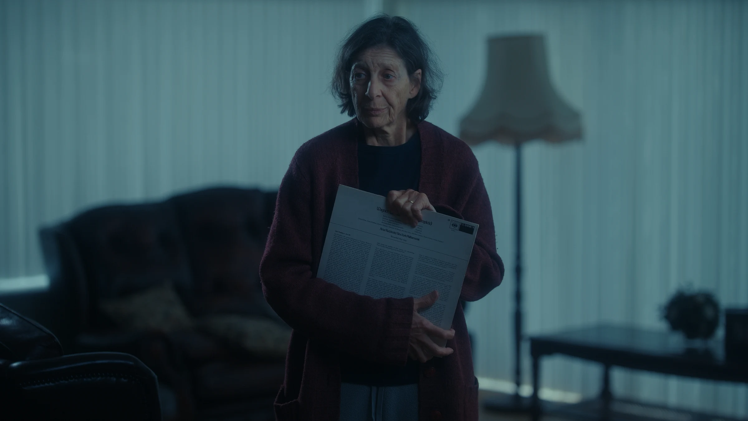 An elderly woman grasps a vinyl that she cannot listen to