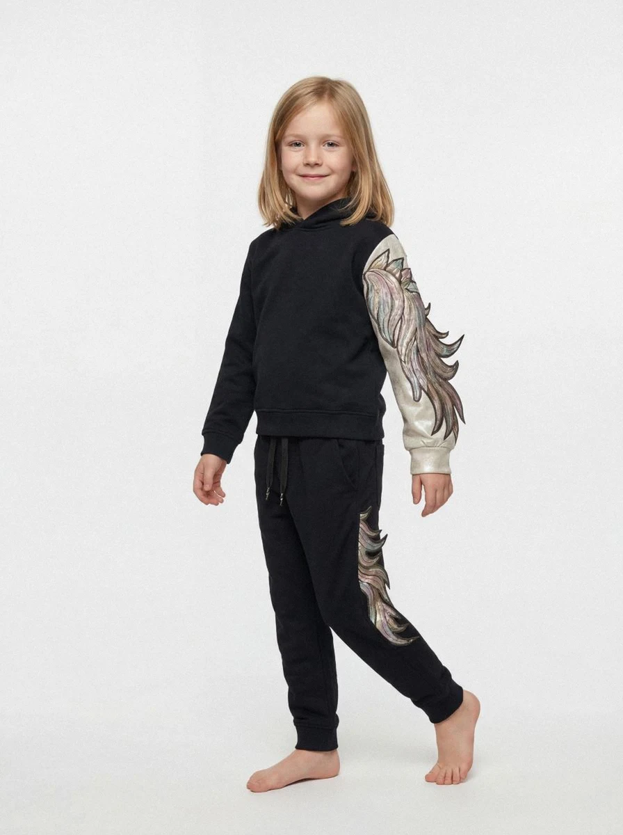 AI generated image with On-Model, A smiling young girl in a black sweatsuit with iridescent wing designs on the sleeves and pants, standing barefoot