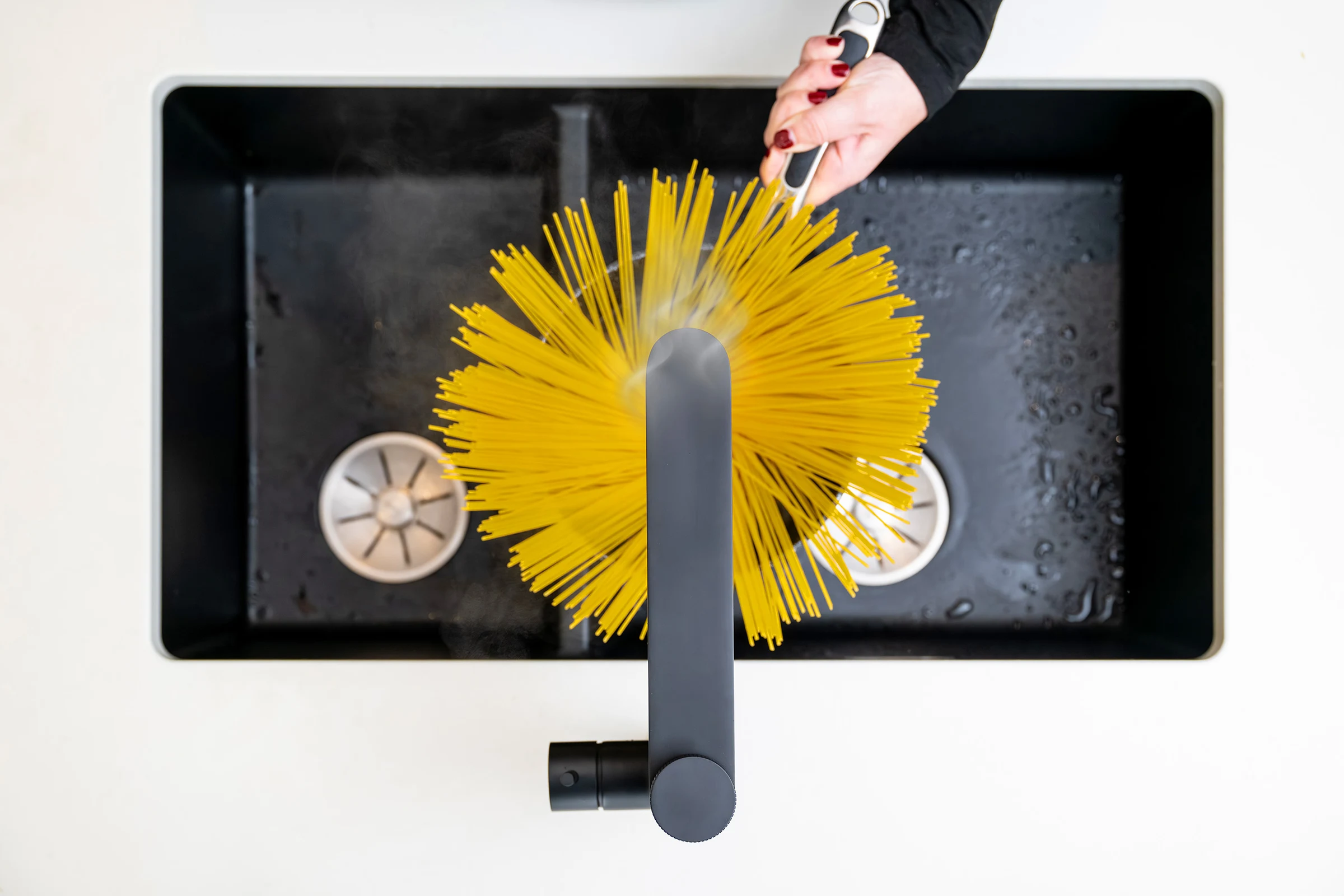 Aquatap Ultimo boiling water tap dispensing instant hot water into a saucepan for pasta preparation, top view kitchen scene