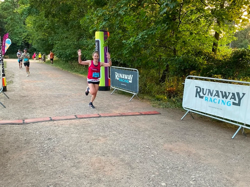 Runner celebrating as she approaches the finish line in the Race the Light 10k race.