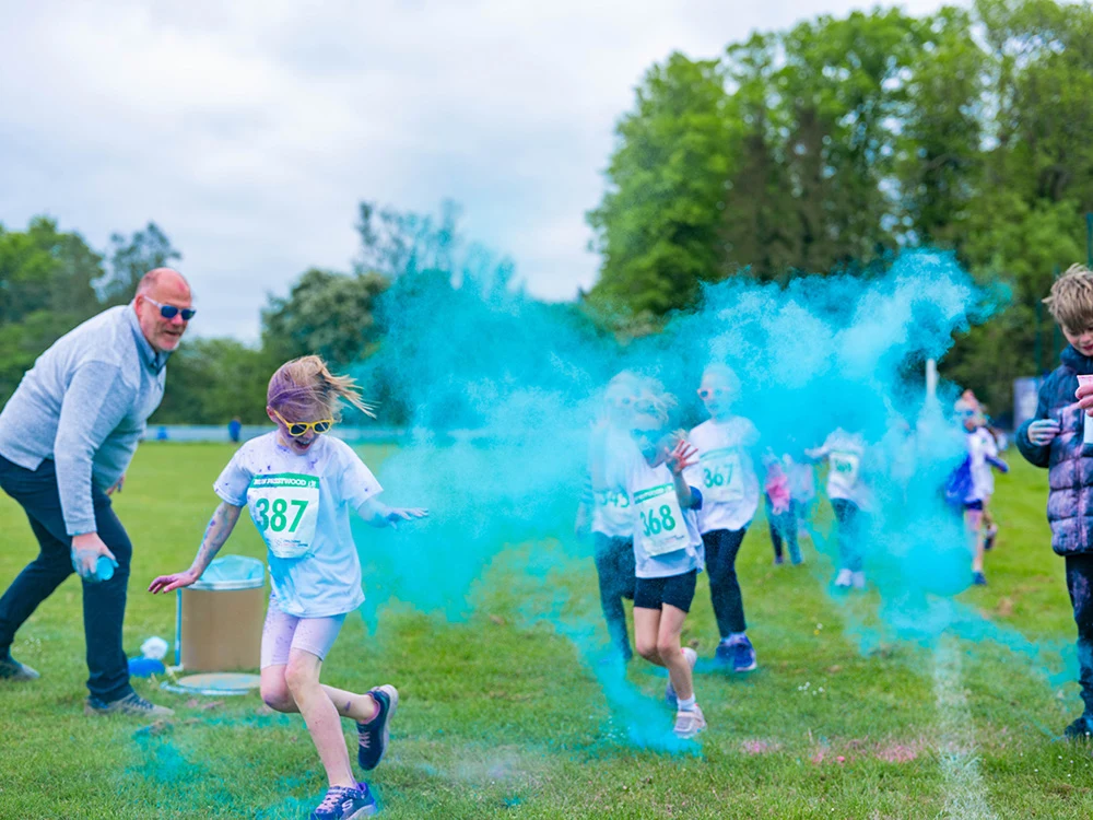 Children taking part in a colour run at Run Prestwood as they run through a cloud of blue powder.