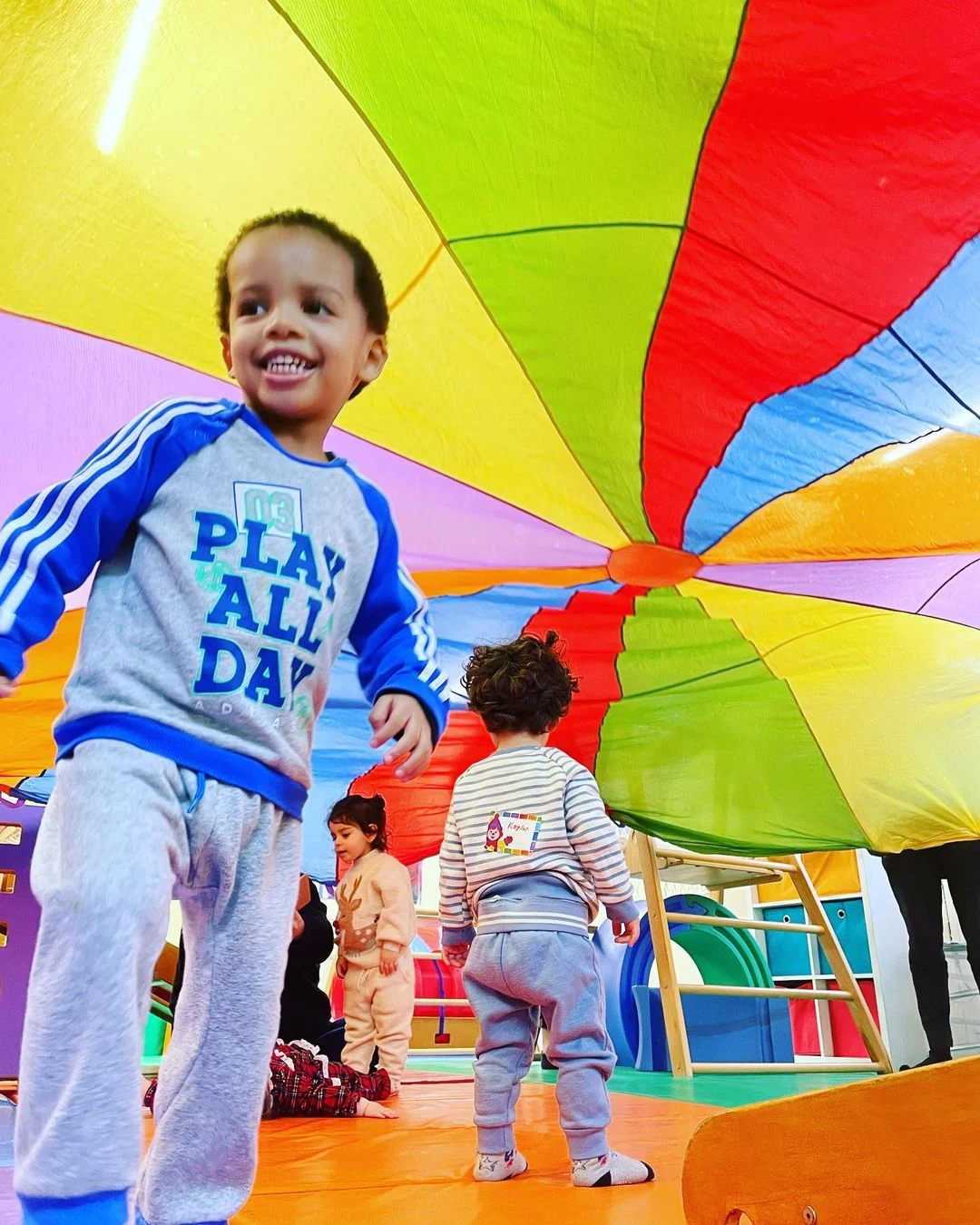 children playing under the parachute in a Gymboree Play & Music class